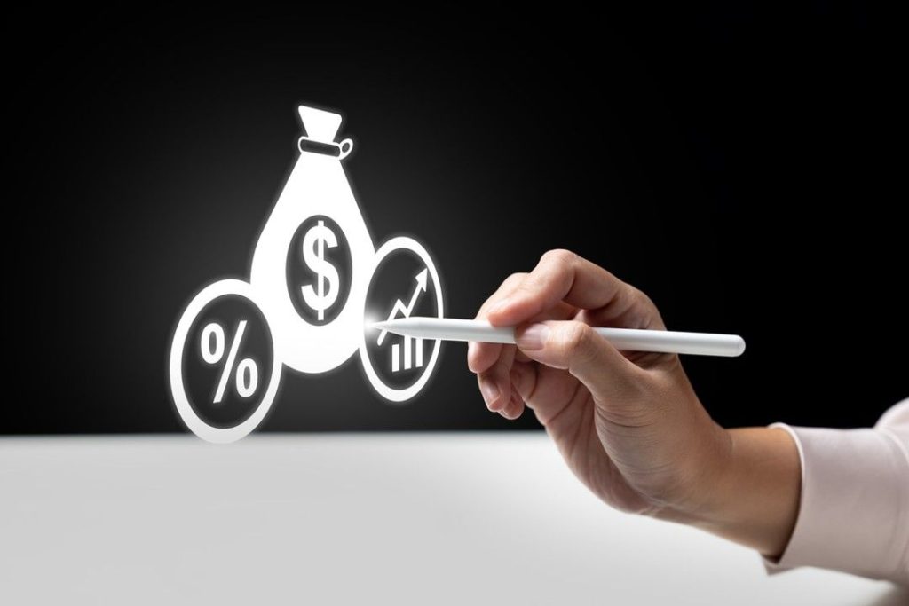Mão segurando uma caneta digital apontando para ícones de dinheiro, porcentagem e gráfico de crescimento, simbolizando conceitos de o que é renda fixa e renda variável e planejamento financeiro.