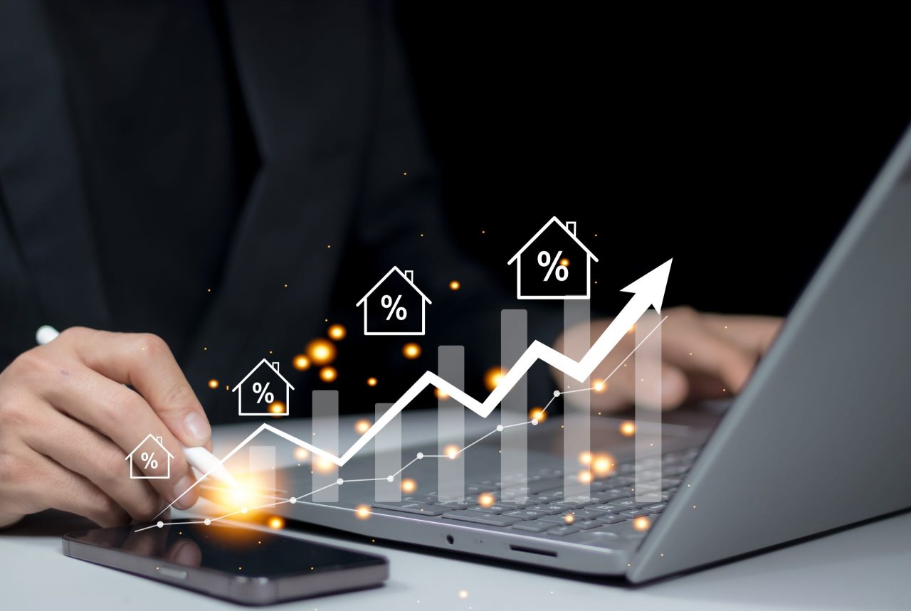 Profissional utilizando notebook com gráfico de crescimento e ícones de juros, ilustrando análise sobre a diferença entre empréstimo e financiamento.